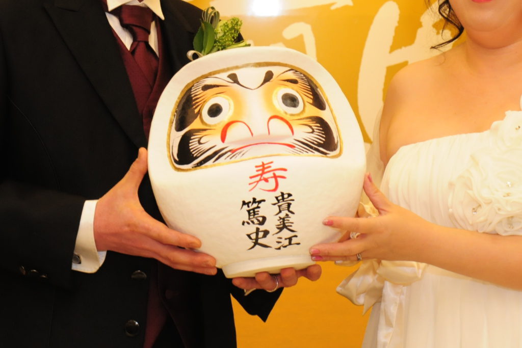 開眼しただるまを持つ新郎新婦